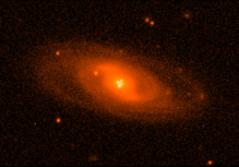 Imagen del sistema lente Q2237+0305 obtenida con el Nordic Optic Telescope en condiciones atmosféricas excelentes. Muestra la imagen de la galaxia espiral que hace de lente gravitatoria. Cerca del núcleo pueden verse las cuatro imágenes del cuásar producidas por el efecto. Imagen: Mediavilla et al. Fuente: UGR.